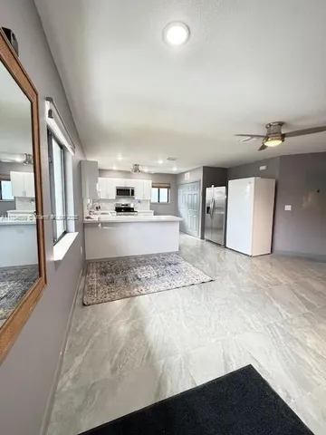 a living room with stainless steel appliances furniture a rug and a large window