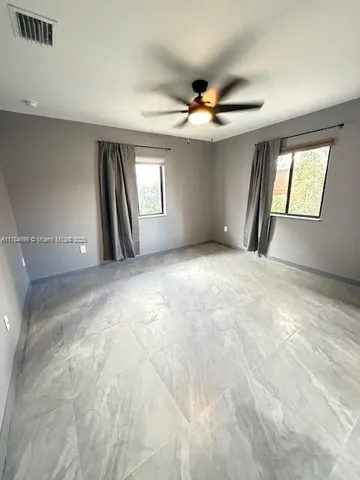 a view of an empty room with window and chandelier fan