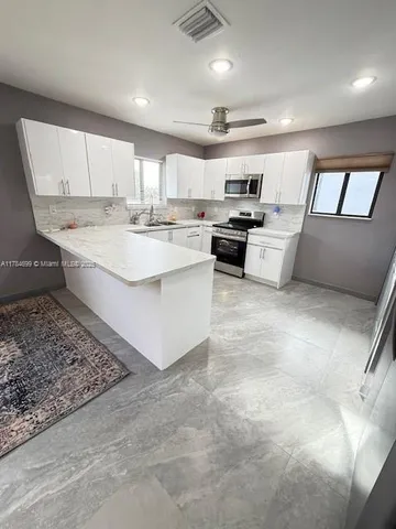 a large white kitchen with sink and white cabinets