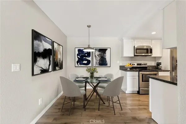 a kitchen with stainless steel appliances granite countertop a stove top oven a sink a dining table and chairs with wooden floor