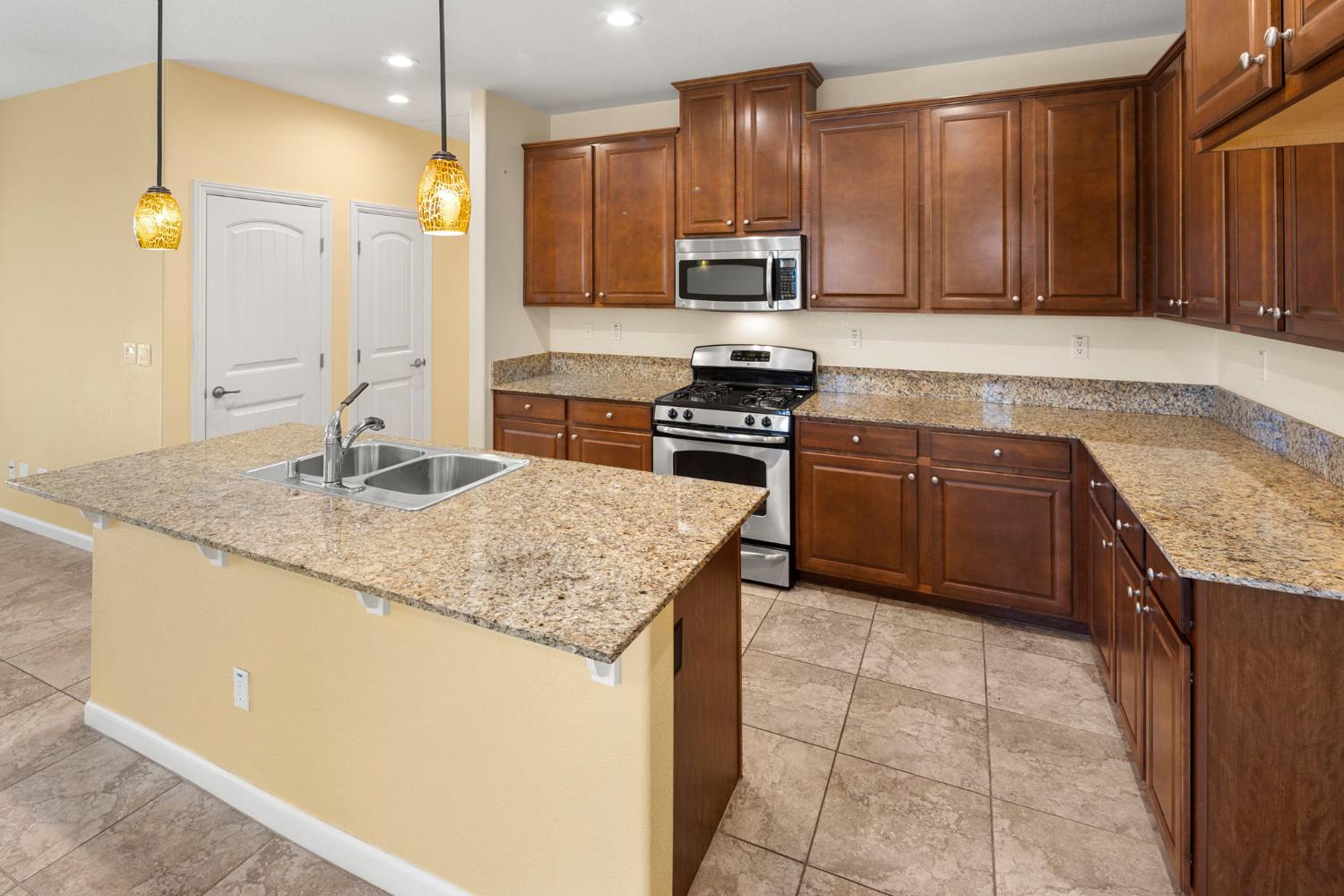 3451 Rainhill Loop Roseville, CA 95747 - Photo 8 of 40 a kitchen with stainless steel appliances granite countertop a sink stove and refrigerator