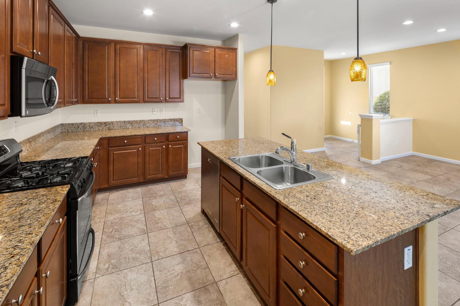 3451 Rainhill Loop Roseville, CA 95747 - Photo 9 of 40 a kitchen with kitchen island granite countertop a sink a counter top space appliances and cabinets