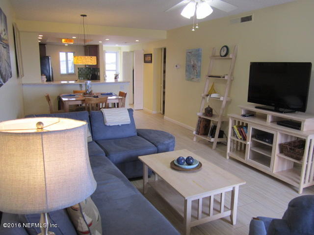 4 Ocean Trace Road, Unit 422 St. Augustine, FL 32080 - Photo 14 of 33 a living room with furniture a flat screen tv and a chandelier
