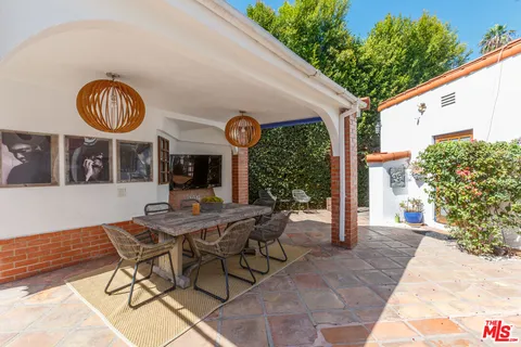 a view of a patio with table and chairs potted plants and palm trees