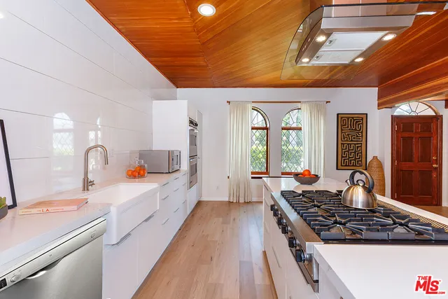 a large kitchen with kitchen island a large window a sink and stainless steel appliances