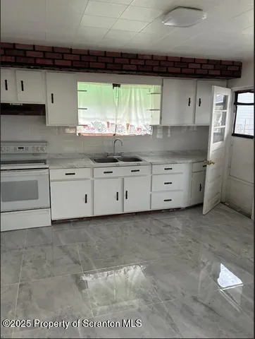 a kitchen with granite countertop a stove a sink and a white cabinets