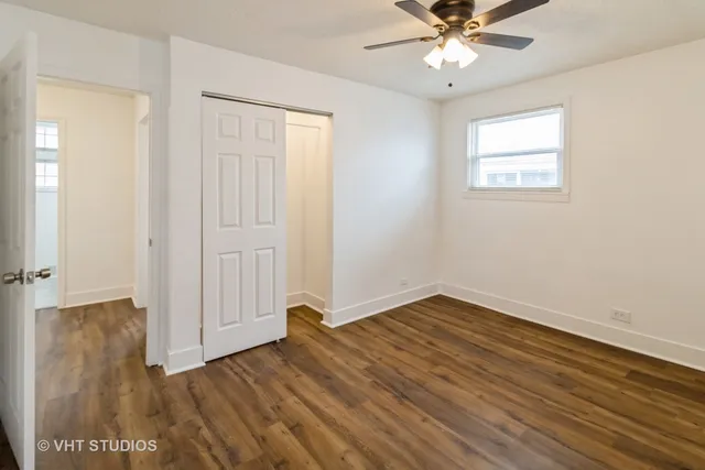 an empty room with wooden floor closet and windows