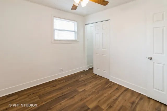 an empty room with wooden floor chandelier fan and windows