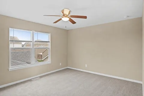 an empty room with windows and fan