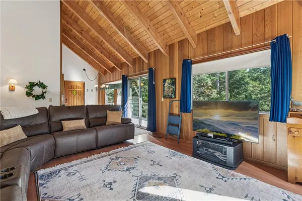 a living room with furniture a flat screen tv and a floor to ceiling window