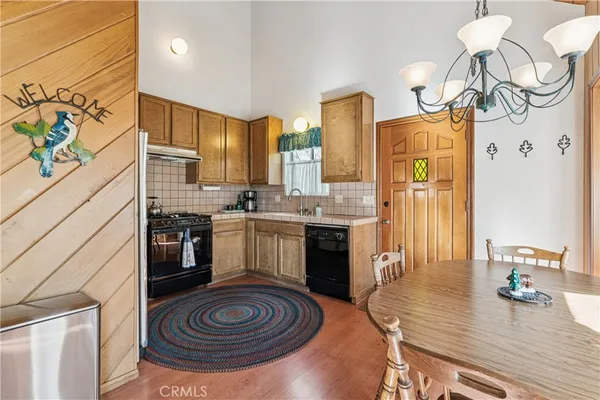 a kitchen with stainless steel appliances a stove a sink dishwasher and a refrigerator with wooden floor