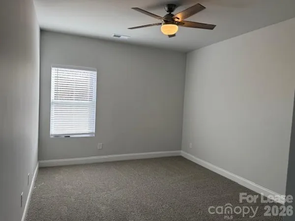 an empty room with a window and a ceiling fan