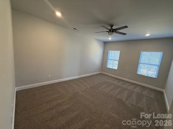 an empty room with windows and fan