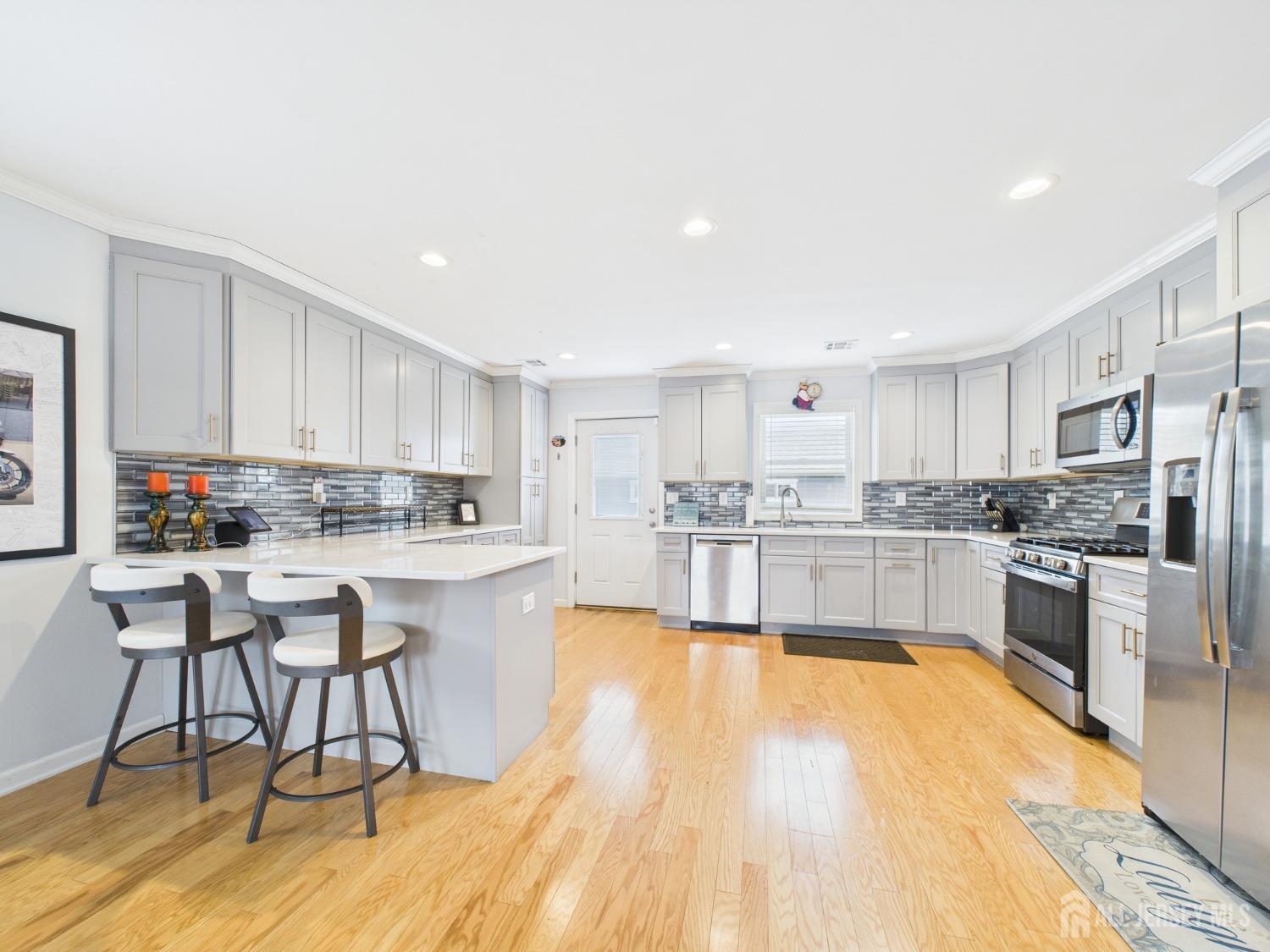 67 Columbus Avenue Edison, NJ 08817 - Photo 5 of 23 a large white kitchen with wooden floor and stainless steel appliances