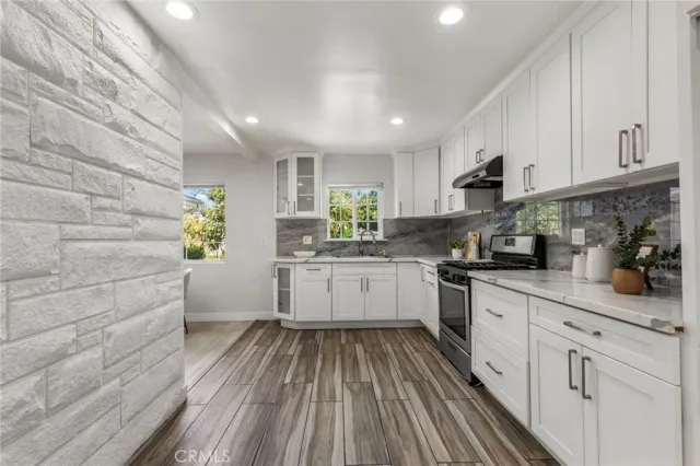 a kitchen with stainless steel appliances granite countertop white cabinets sink and window