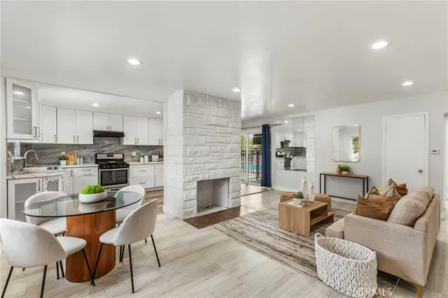 a living room with furniture and a fireplace with kitchen view