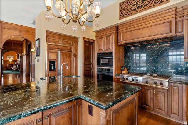5615 East Eight Mile Gap Road Kanab, UT 84741 - Photo 11 of 81 Kitchen featuring wood finish cabinets, arched walkways, dark stone counters, a chandelier, and tasteful backsplash