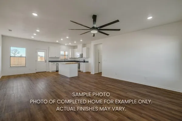 a view of kitchen and empty room with wooden floor