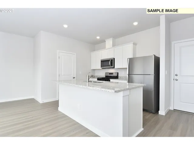 a kitchen with kitchen island a refrigerator sink and wooden floor