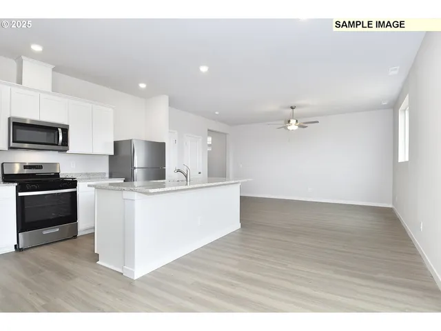 a living room with stainless steel appliances kitchen island granite countertop a sink a stove top oven a counter space and cabinets
