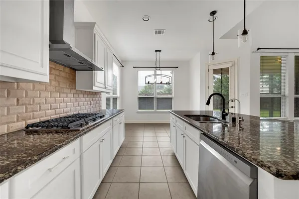 a large kitchen with granite countertop a stove and a sink