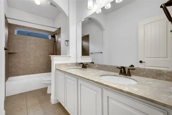 a bathroom with a granite countertop sink a toilet mirror and bathtub