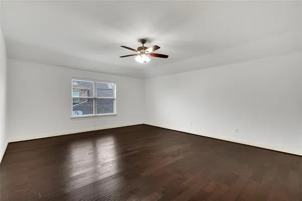 a view of a room with wooden floor and a ceiling fan
