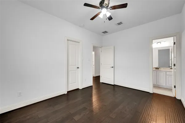 an empty room with wooden floor cabinet and a ceiling fan
