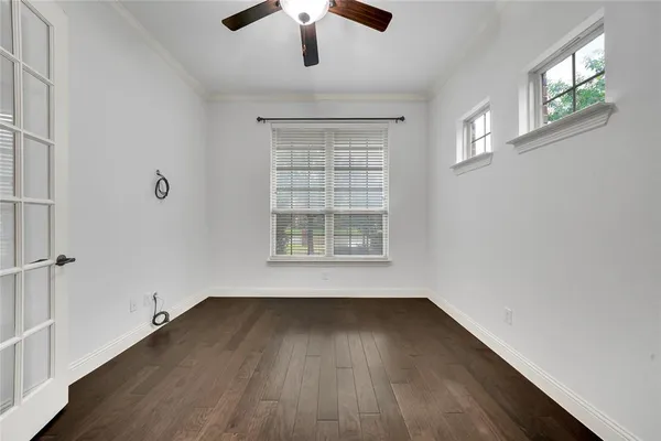 an empty room with wooden floor chandelier fan and windows