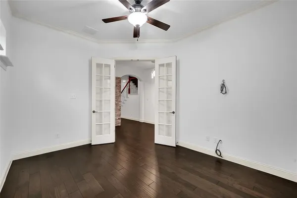 a view of an empty room with wooden floor and a ceiling fan
