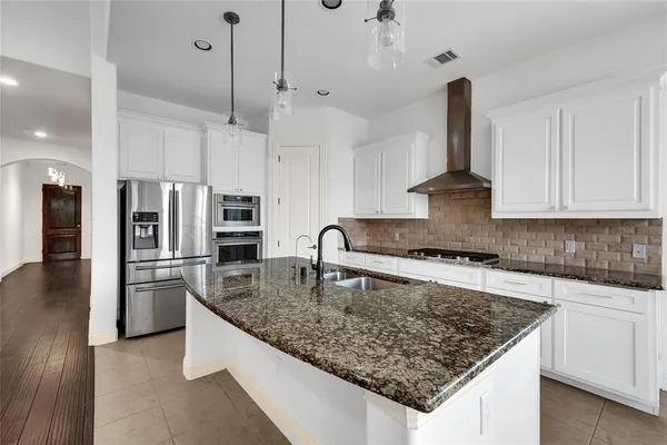 a kitchen with stainless steel appliances granite countertop a sink a stove and a refrigerator