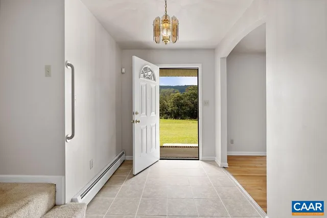 an empty room with wooden floor chandelier and windows