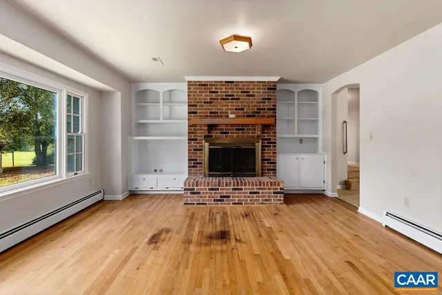 an empty room with wooden floor & window