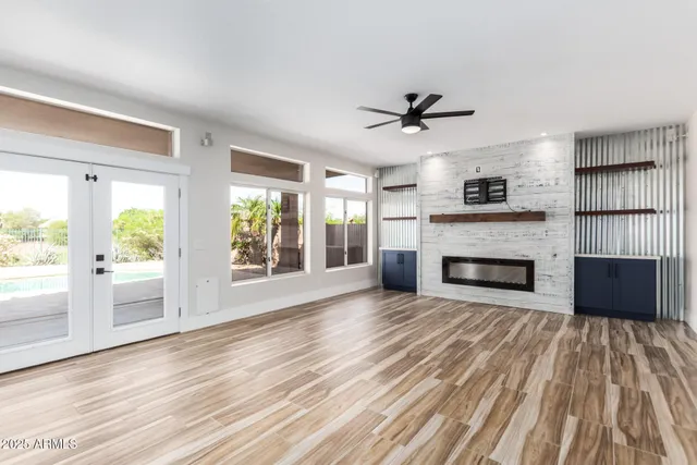 a view of an empty room with wooden floor fireplace and a window