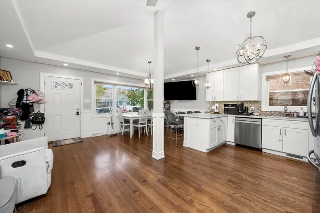 a kitchen with stainless steel appliances a stove top oven a sink dishwasher and a dining table with wooden floor