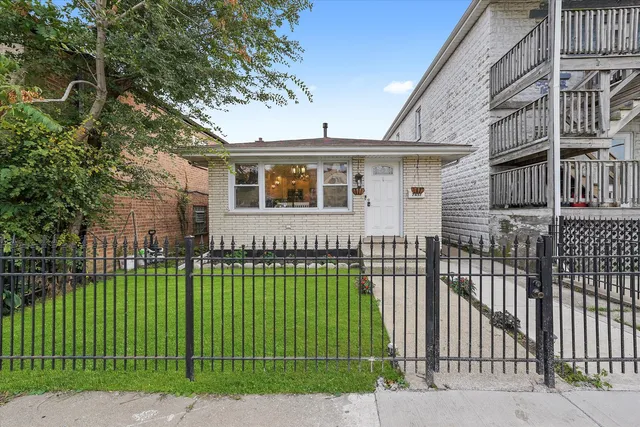 a view of a white house with a big yard and plants