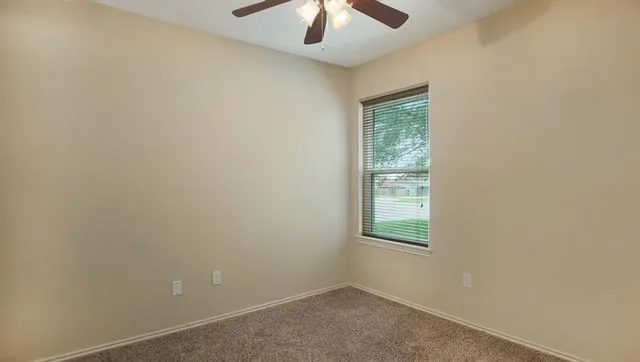 an empty room with a window and a fan