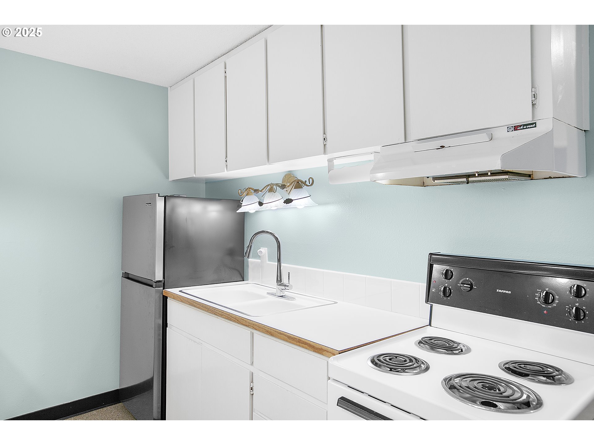 48988 Highway 101, Unit 137F Neskowin, OR 97149 - Photo 12 of 29 a kitchen with a sink a stove and white cabinets