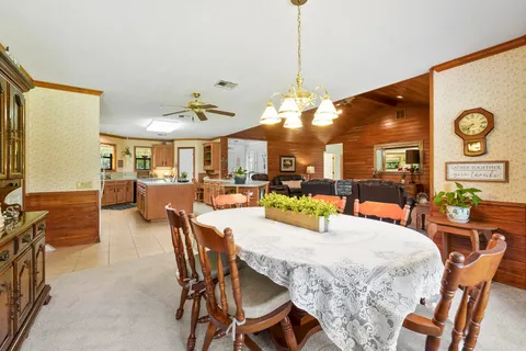 a view of a dining room and livingroom with furniture wooden floor a chandelier