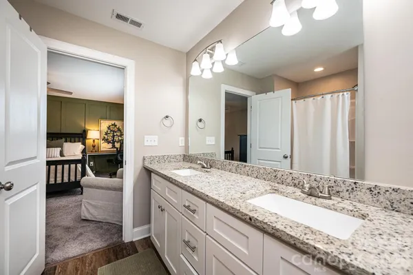 a spacious bathroom with a granite countertop sink a mirror and a shower