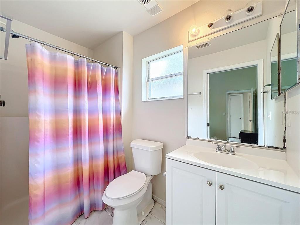5633 Piney Ridge Drive Orlando, FL 32808 - Photo 12 of 18 a bathroom with a sink a toilet and shower curtain