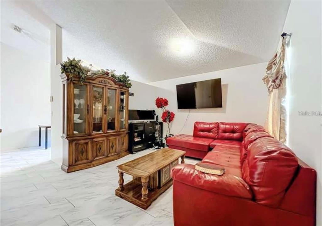 5633 Piney Ridge Drive Orlando, FL 32808 - Photo 4 of 18 a living room with furniture and a flat screen tv