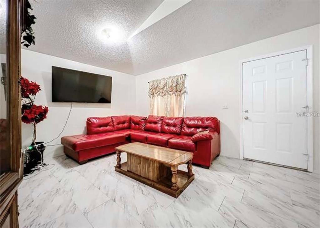 5633 Piney Ridge Drive Orlando, FL 32808 - Photo 5 of 18 a living room with furniture and a flat screen tv
