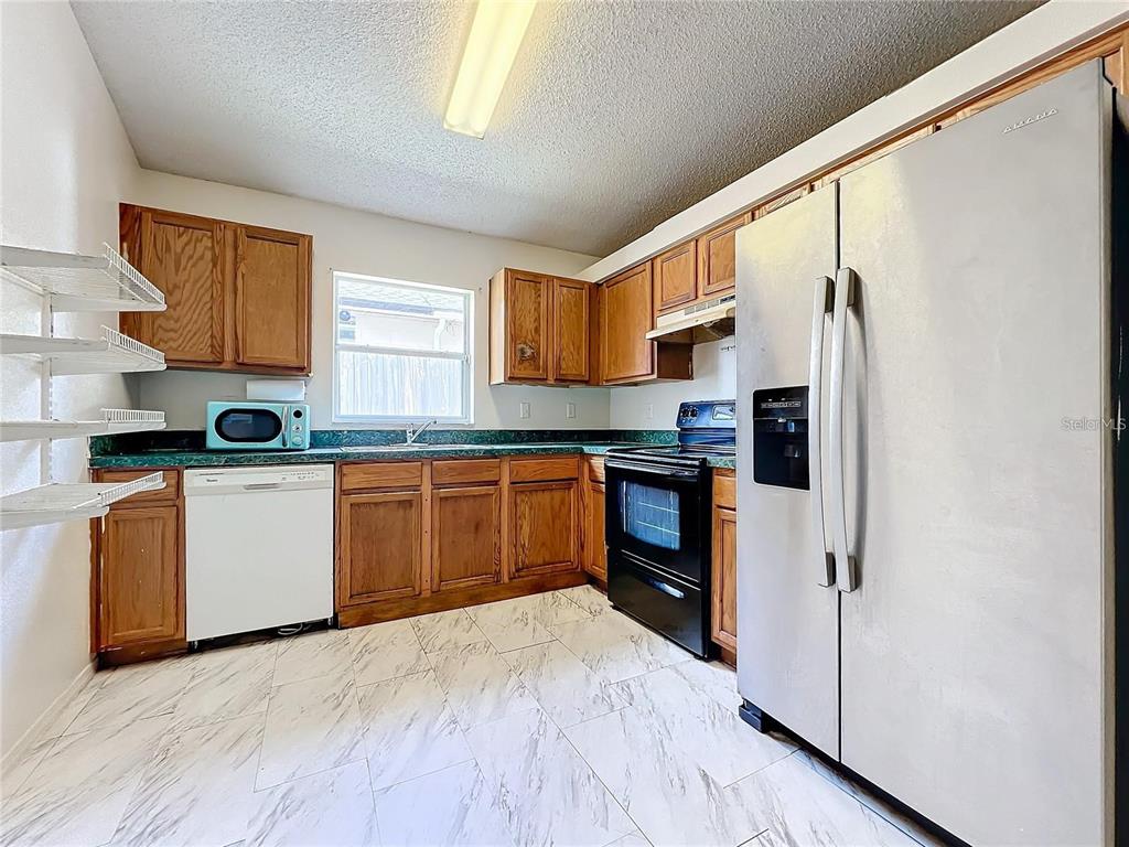 5633 Piney Ridge Drive Orlando, FL 32808 - Photo 8 of 18 a kitchen with stainless steel appliances granite countertop a refrigerator sink and wooden cabinets