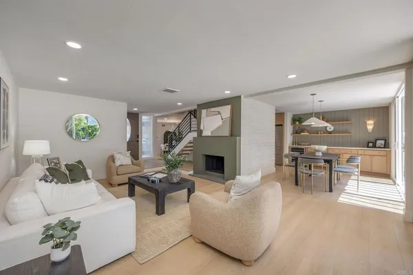a living room with fireplace furniture and a dining table with wooden floor