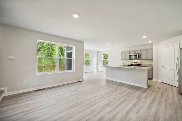 a view of kitchen with kitchen island wooden floors and stainless steel appliances