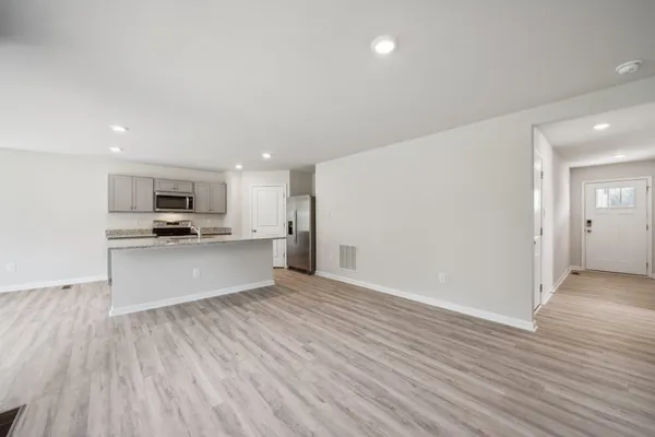 a view of kitchen with kitchen island wooden floors and stainless steel appliances