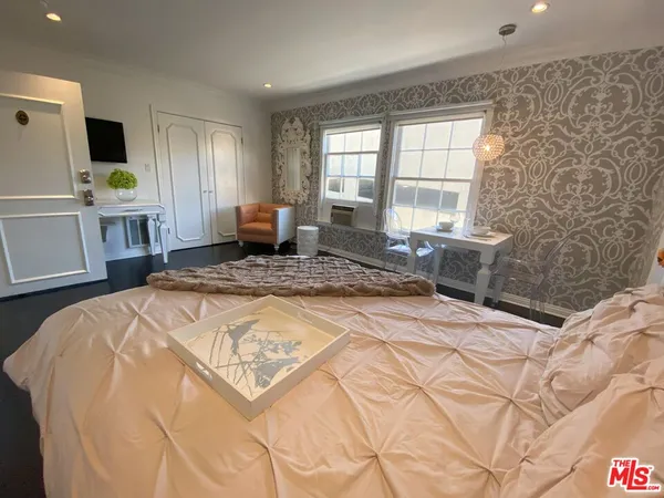 a spacious bedroom with a bed a window and a flat screen tv