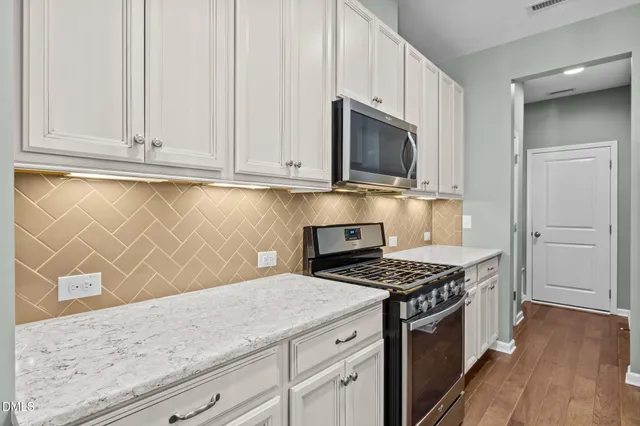 a kitchen with granite countertop white cabinets and stainless steel appliances