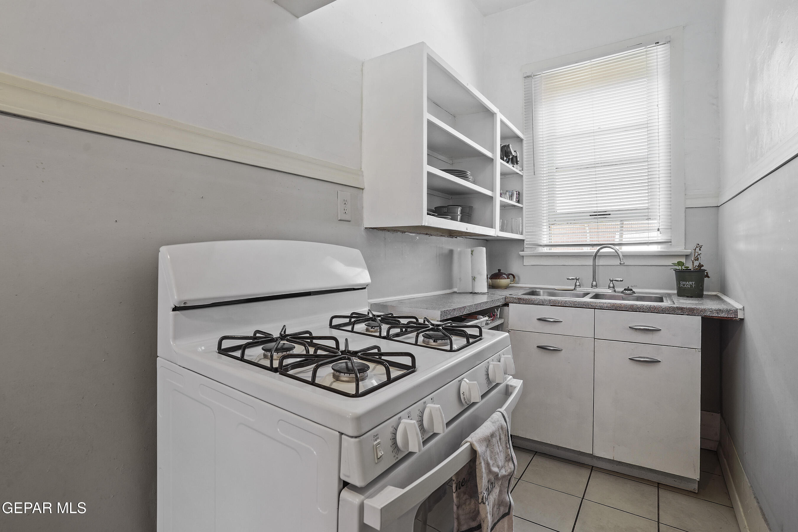 1207 East Rio Grande Avenue El Paso, TX 79902 - Photo 12 of 43 a white kitchen with stainless steel appliances granite countertop a stove and a sink